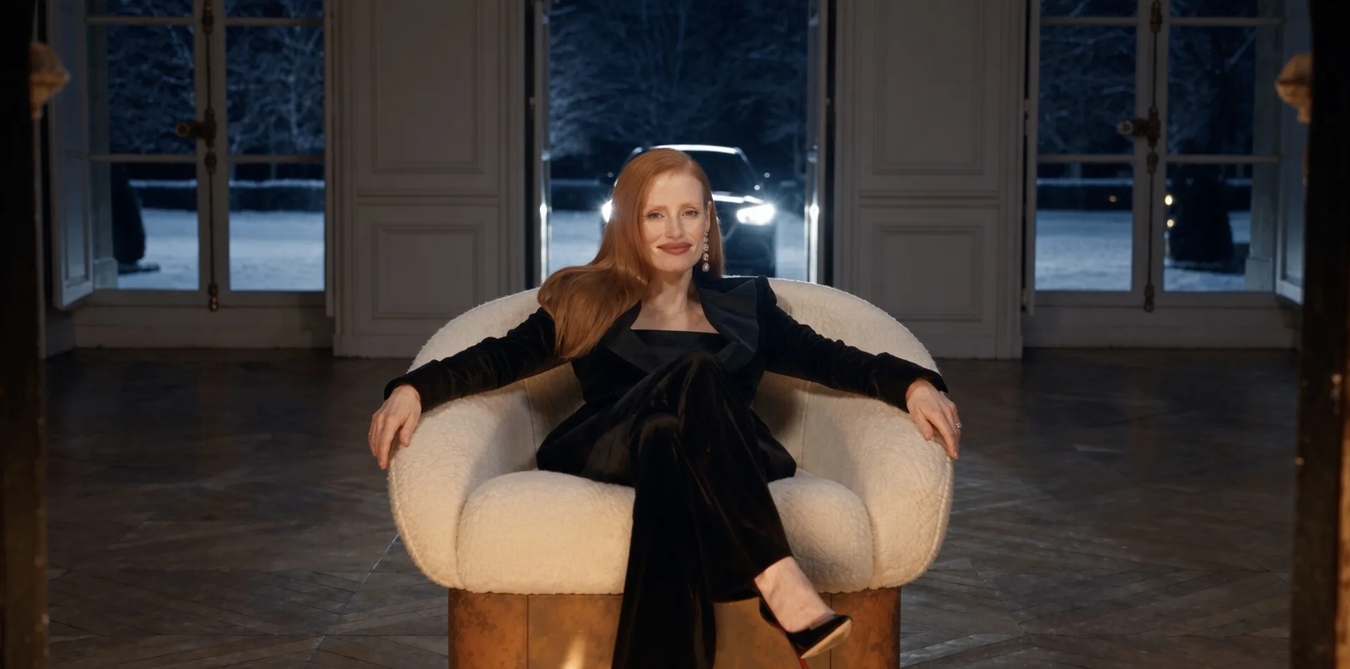 Hestia armchair in Corten steel, a woman with her arms on the armrests, car headlights beyond the windows